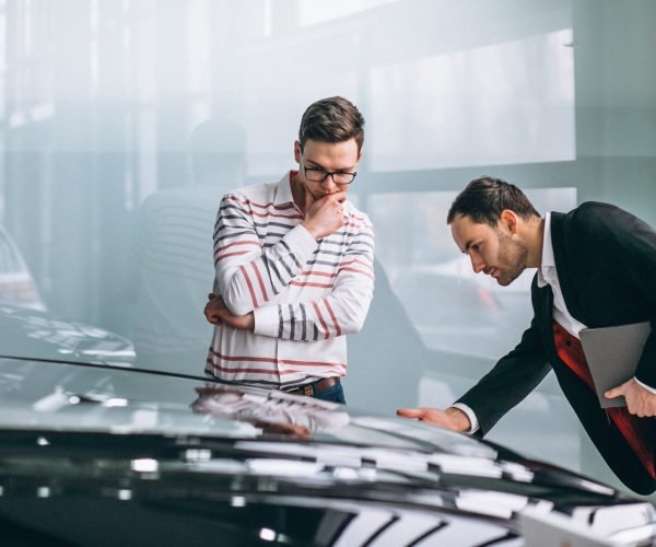 Salesman at a car showroom selling a car